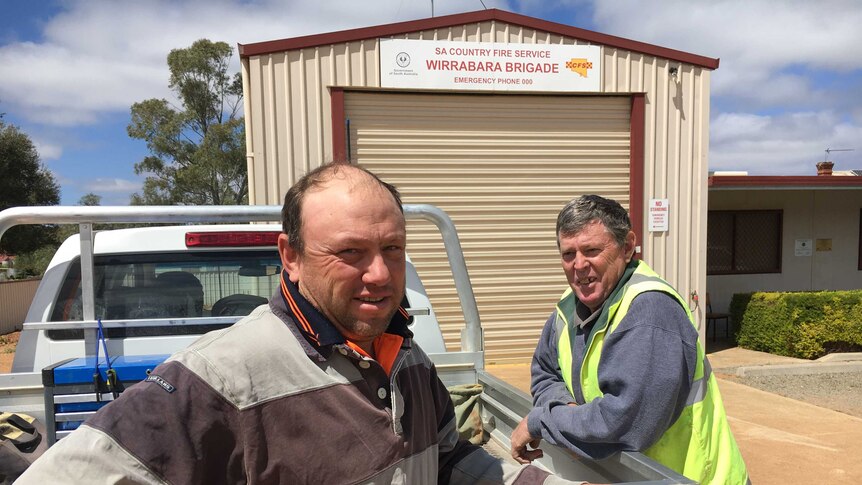 Two men leaning on a ute outside a CFS station.