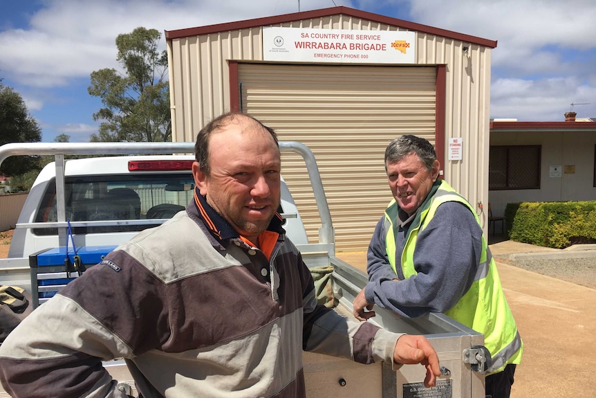 Two men leaning on a ute outside a CFS station.