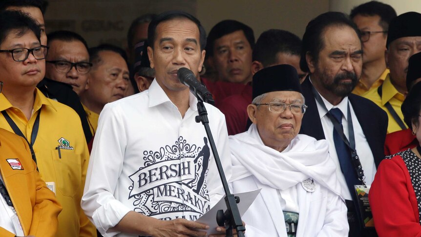 Indonesian President Joko "Jokowi" Widodo, center left, speaks as his running mate Ma'ruf Amin, center right, listens.