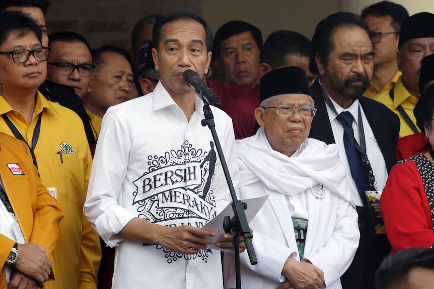 Indonesian President Joko "Jokowi" Widodo, center left, speaks as his running mate Ma'ruf Amin, center right, listens.