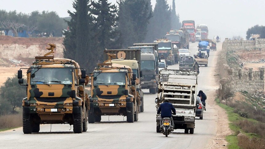 Turkish military convoy drives down the road as civilian vehicles head the other way.