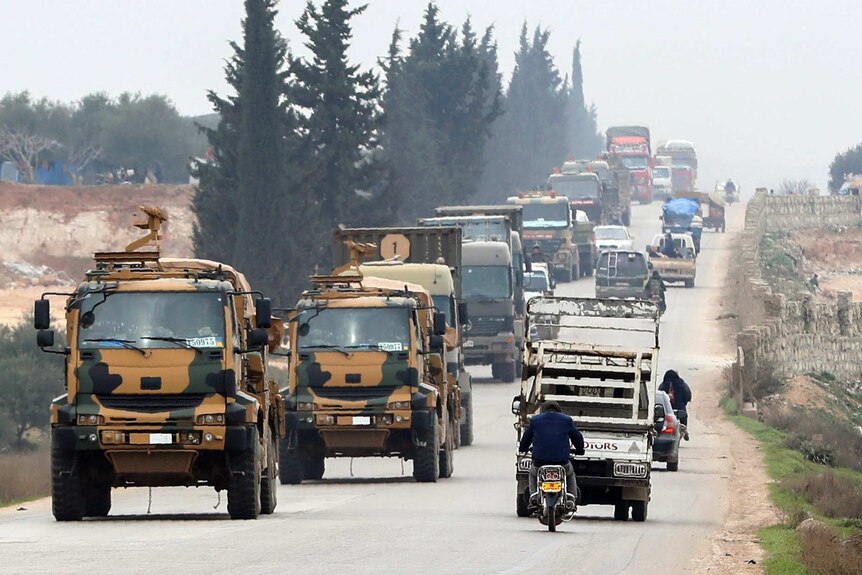 Turkish military convoy drives down the road as civilian vehicles head the other way.