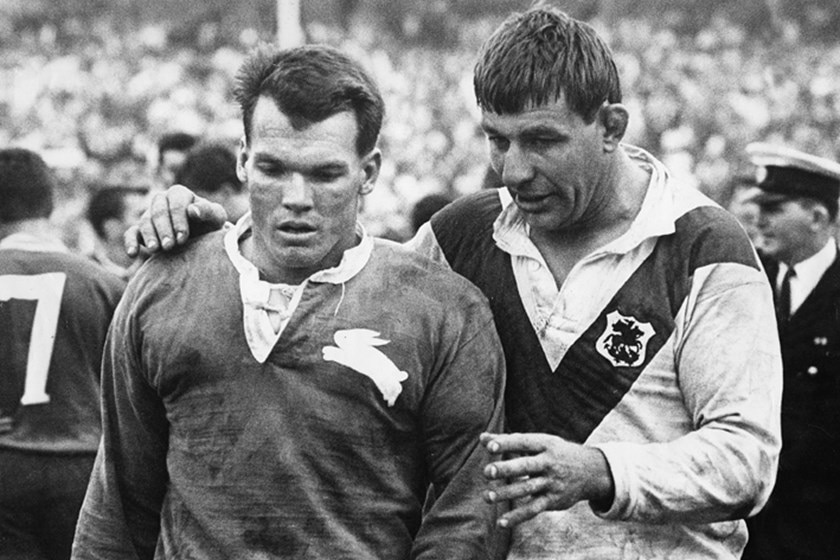 A black and white photo of Brian James on the football field with a St George player.