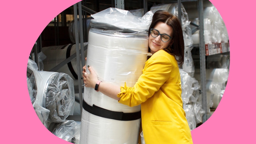 A young woman hugging a vacuum-packed mattress.
