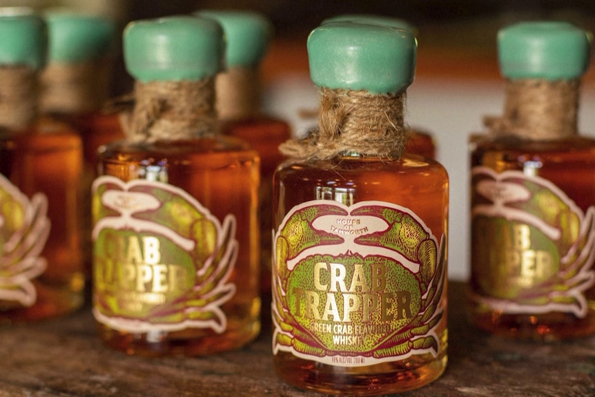 kleine whiskyflessen op een tafel met groene doppen en Crab Trapper-labels erop