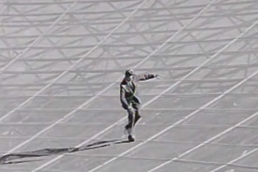 A black and white photo of someone running inside the dish of the Parkes telescope.