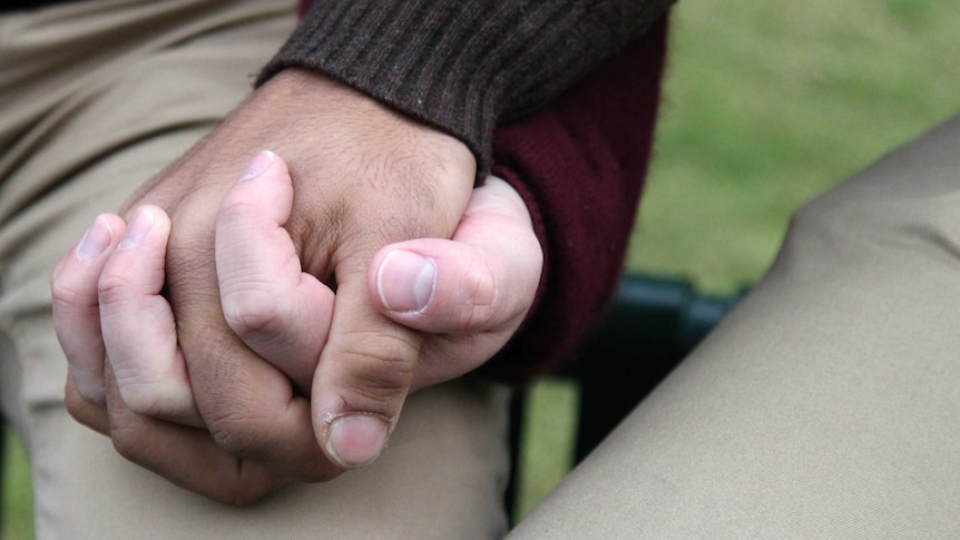 A close-up of two men's hands clasped together.