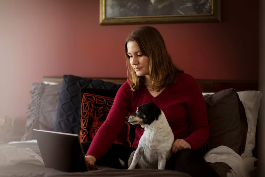 Woman sits on bed with dog