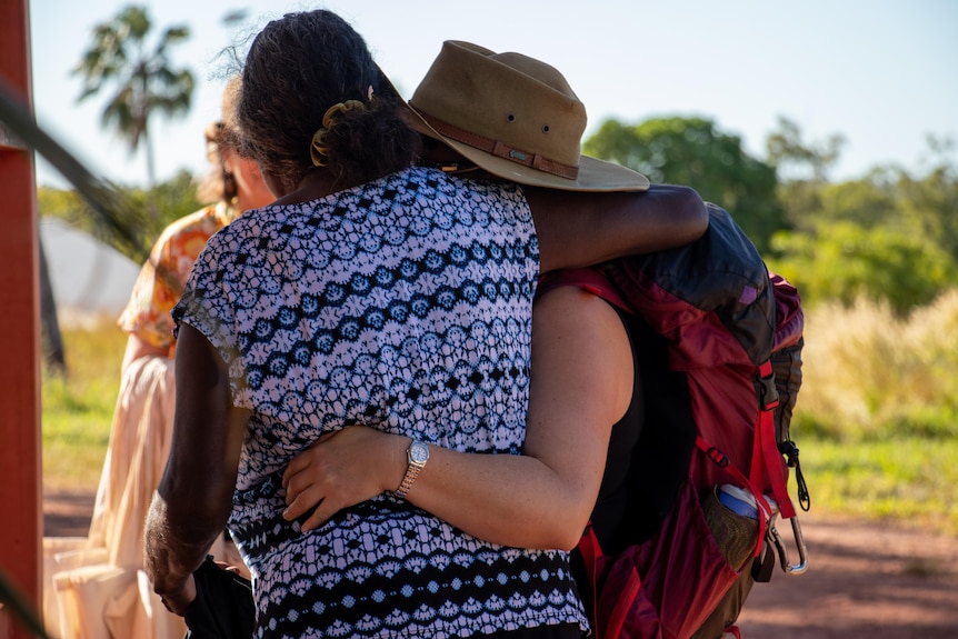 Two women embrace with their arms around each other.