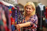 A woman checks through dresses in a women's clothing shop
