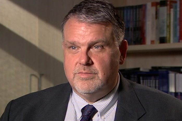 A man in a suit is seated inside an office during an interview