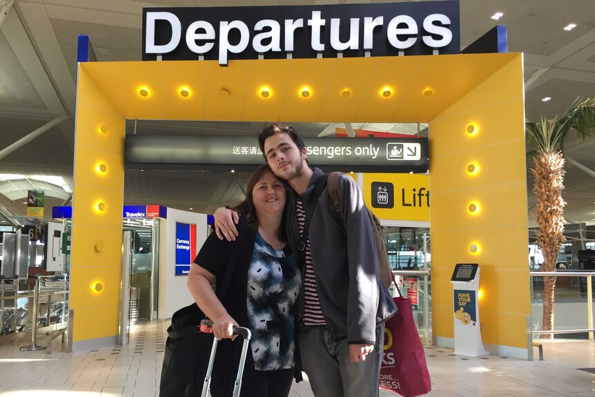 Teenage son and his mum hugging at the airport departure gate.