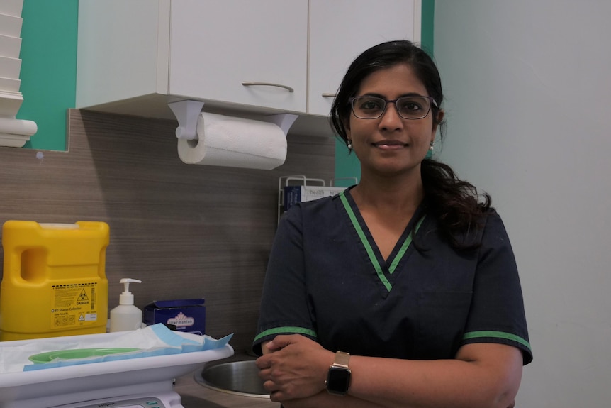 A doctor stands in front of medical equipment in her clinic