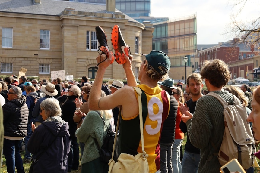 A man at a rally holds up football boots