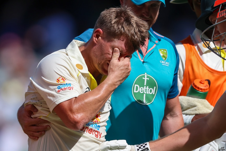 David Warner wipes his eyes as he is led from the field during a Test against South Africa after suffering severe cramping.