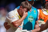 Australia batter David Warner wipes his eyes as he is led from the field during a Test against South Africa.
