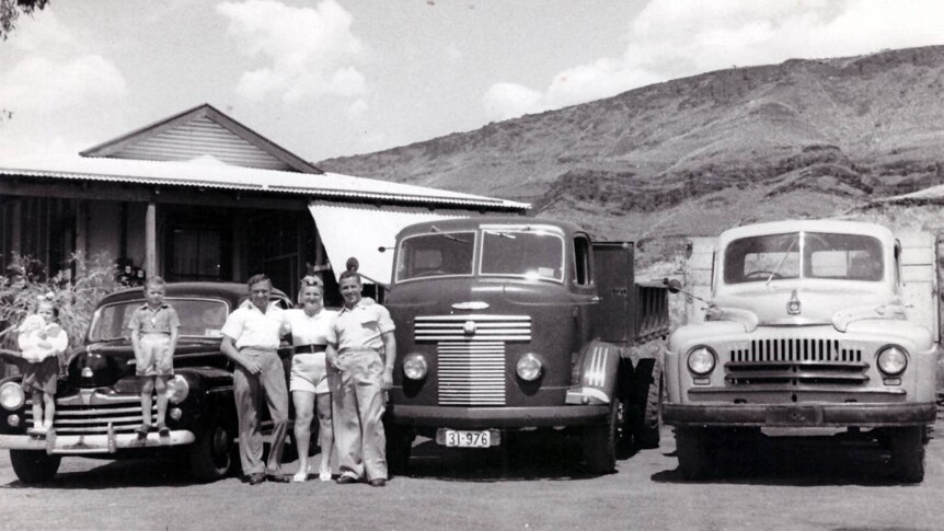 A group of people stand in front of a line of trucks