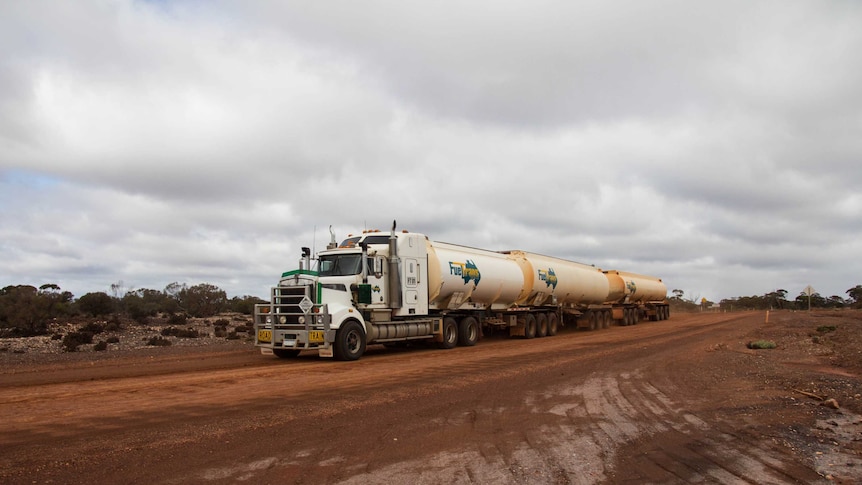A road train travels down an unsealed road outside of Kalgoorlie, Western Australia.
