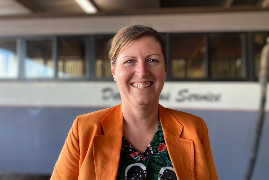 A woman smiling in an orange blazer