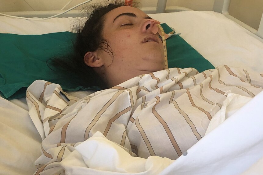 A woman lies unconscious on a hospital bed