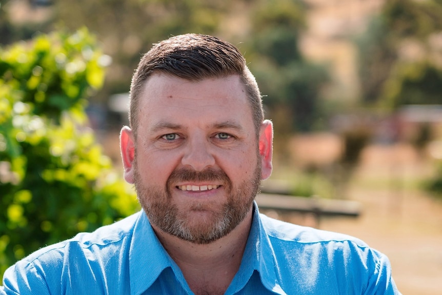 Man wearing a blue shirt looks at the camera