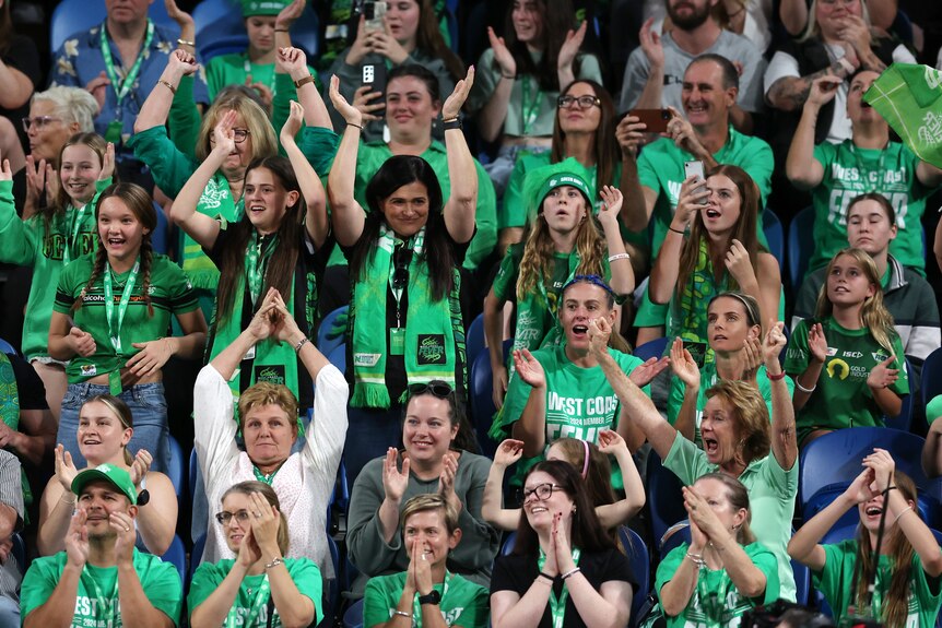 Women, men and girls cheer on the Fever from their seats wearing green