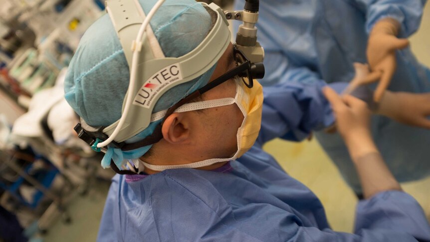 View of the side of a surgeon's head, his medical gown and head covering is on