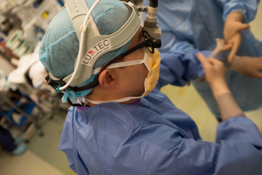 View of the side of a surgeon's head, his medical gown and head covering is on