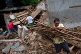 A man carries wood from a damaged building.