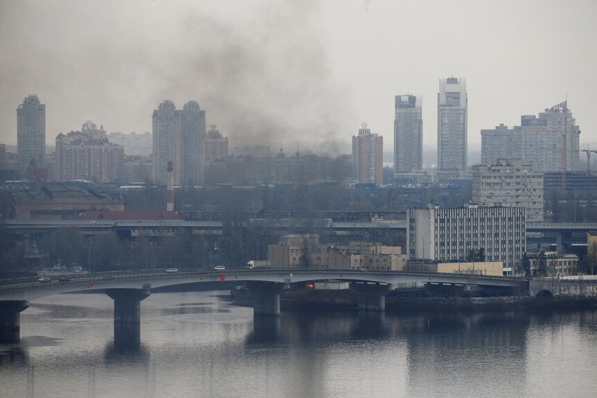 Smoke rises from a collection of buildings next to a bridge in the Ukrainian city of Kyiv