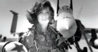 Tammie in her aviation gear, holding her helmet in front of an aircraft