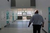 Prison guard walks along corridor at AMC past cells