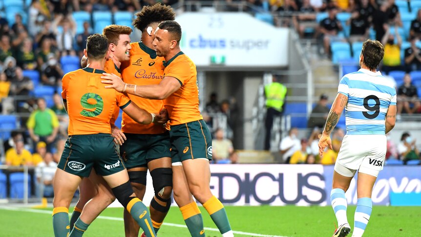 Wallabies players hug Andrew Kellaway on a try as Argentina's number nine walks away.