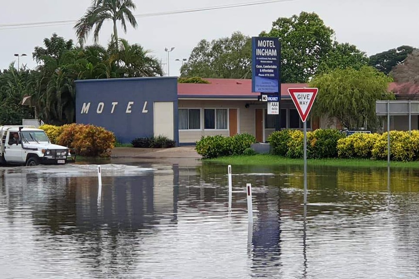 A ute attempts to drive through floodwaters outside Motel Ingham.
