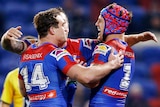 Three Newcastle Knights NRL players embrace as they celebrate a try.