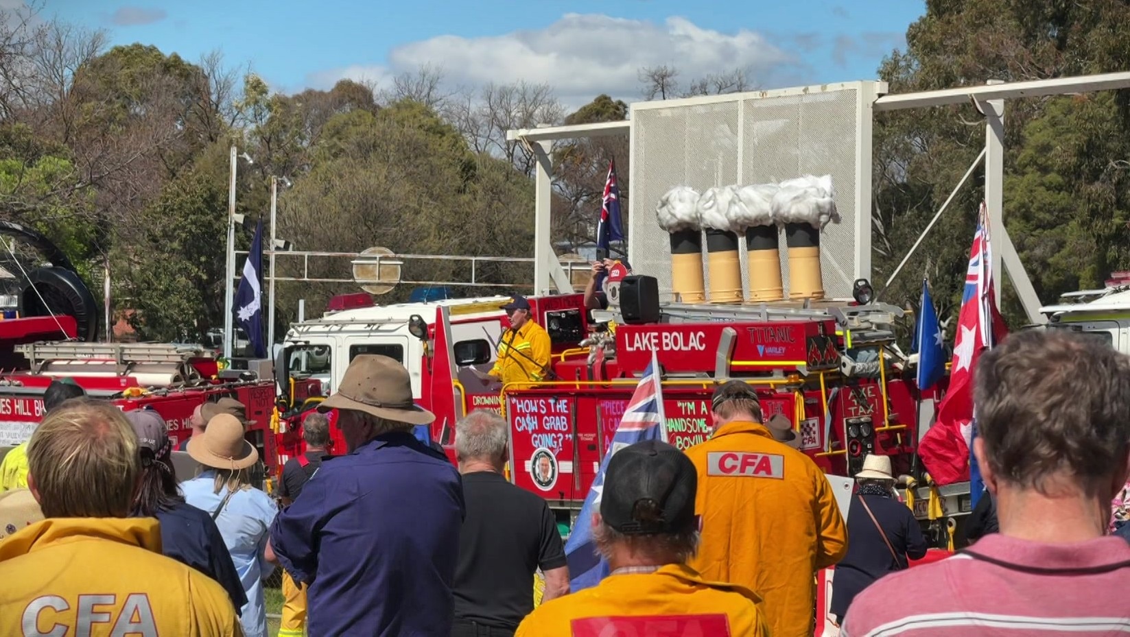 People watch on as a man stands on a fire truck adorned with protest slogans.