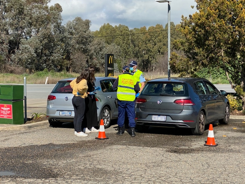 NSW Police officers speak to people in cars at McDonald's in Gundagai.