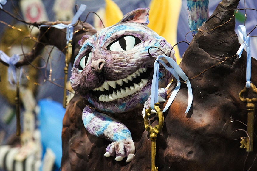 A sugar sculpture of the purple and blue Cheshire Cat from Alice and Wonderland.