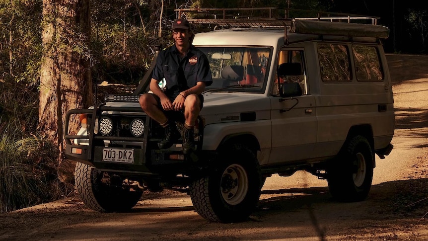 A young man with brown hair sits on a Troopy 4WD.