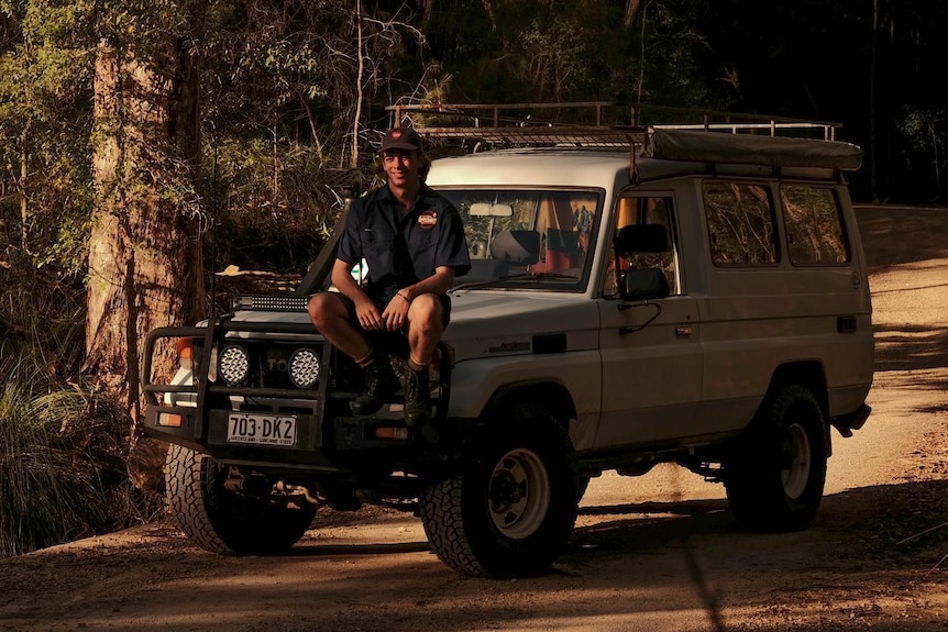 A young man with brown hair sits on a Troopy 4WD.