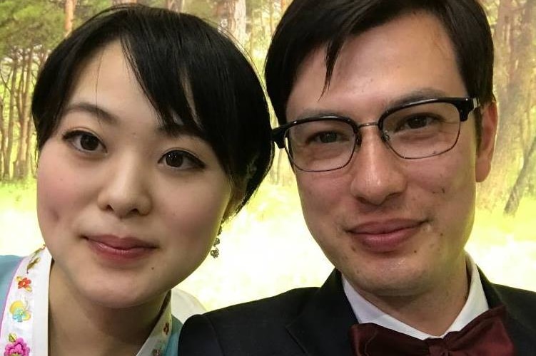 A selfie of a smiling man and woman with a forest in the background.