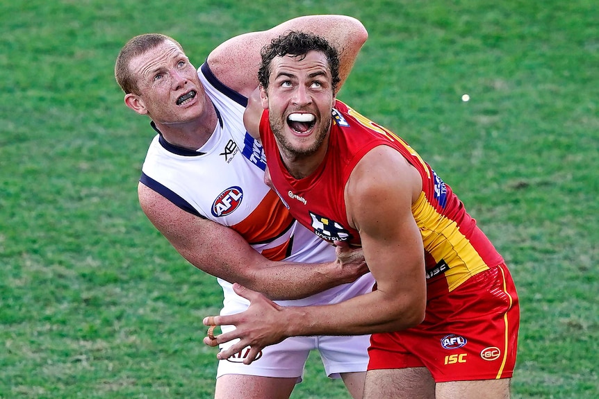 Jarrod Witts and Sam Jacobs are tangled up and looking upwards at a ball (out of picture)