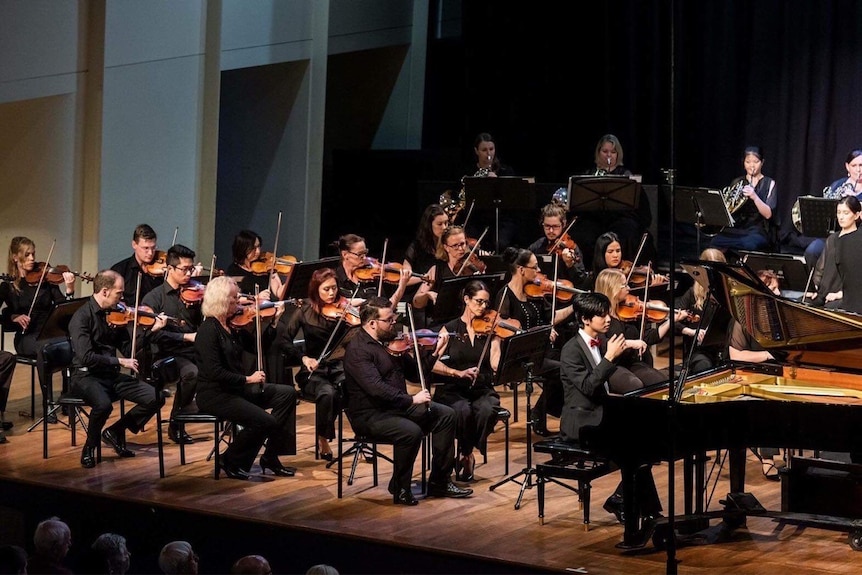 Orchestra playing on concert hall stage.