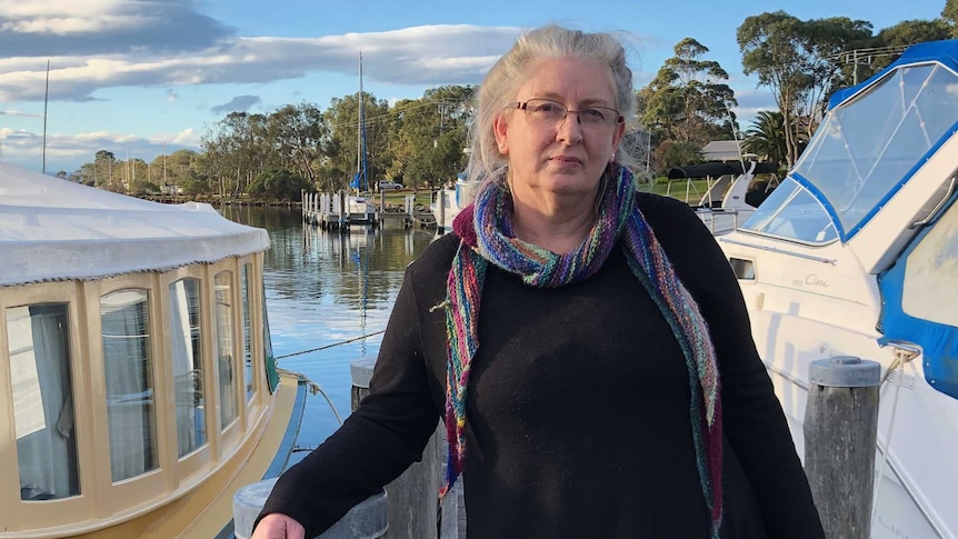 Terri Eskdale stands on a pier in front of two boats.