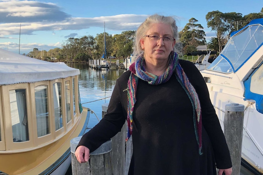 Terri Eskdale stands on a pier in front of two boats.