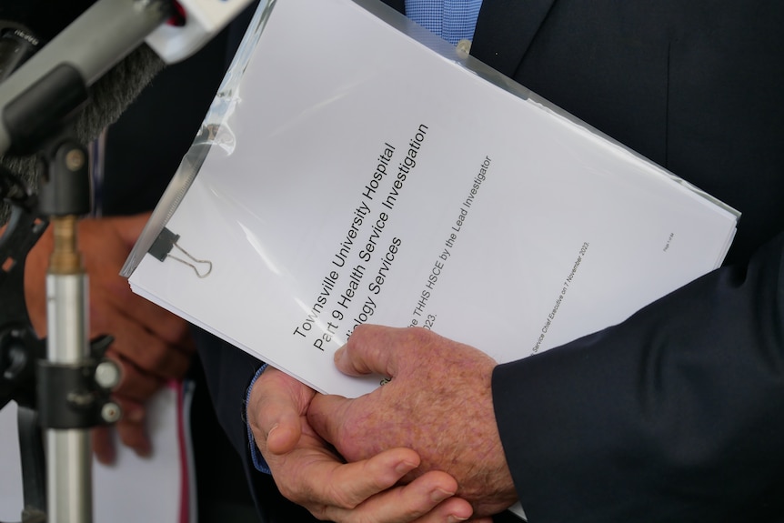 Two hands holding a report in a plastic folder. It reads Townsville University Hospital. 