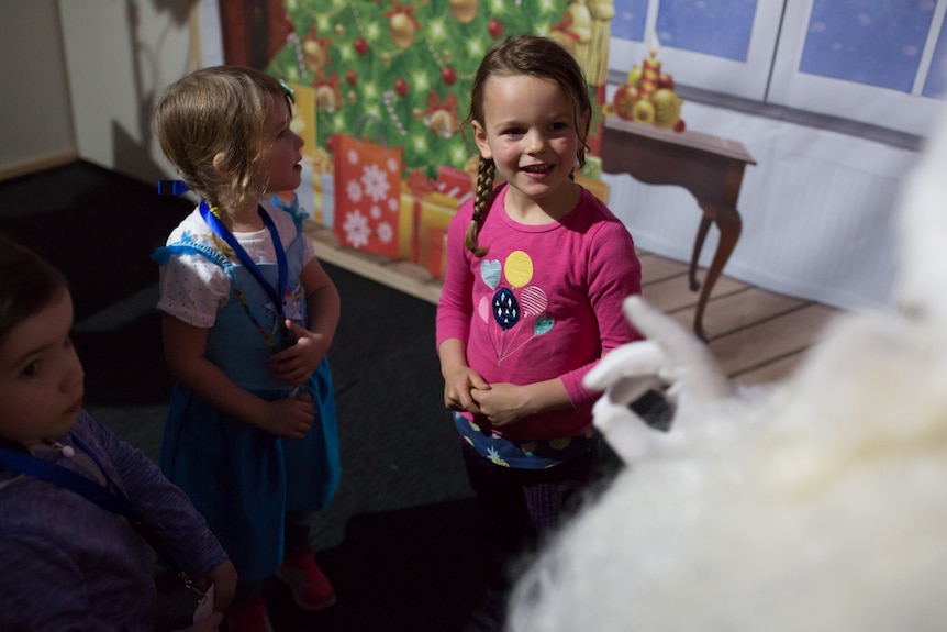 Three little girls are captivated by a chat with Santa.