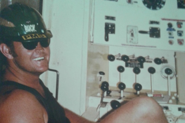 Tyrone Buckton sitting in front of a panel of switches and dials at work at the mine