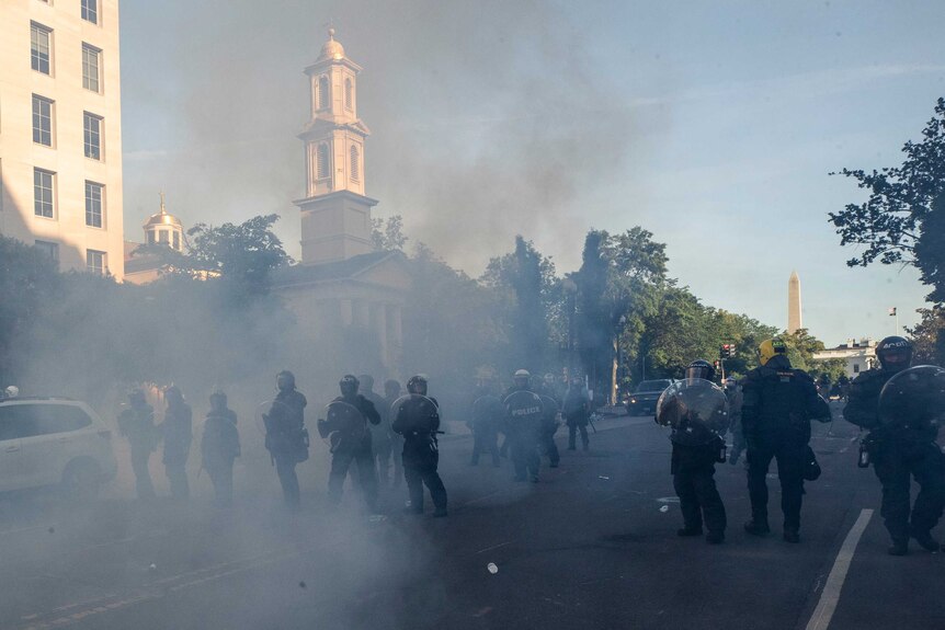 Tear gas floats in the air as a line of police move demonstrators away from St. John's Church across Lafayette Park.