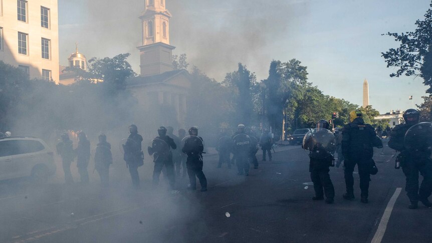 Tear gas floats in the air as a line of police move demonstrators away from St. John's Church across Lafayette Park.